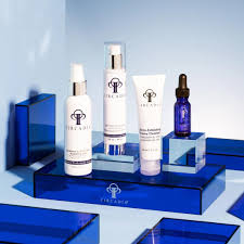 Four skincare products, including white bottles, tubes, and a blue dropper bottle, displayed on glossy blue geometric blocks against a light blue studio background. Circadia